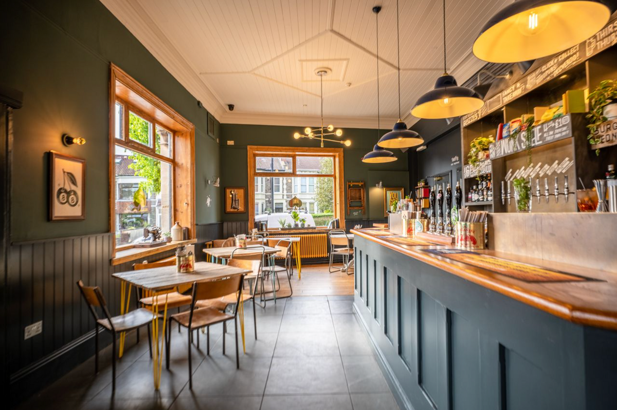 Interior of The All Inn with a long bar, pendant lights and tables by the windows