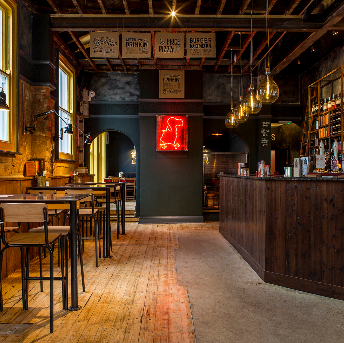 Interior of a cozy restaurant with wooden floors, tables, and a bar.
