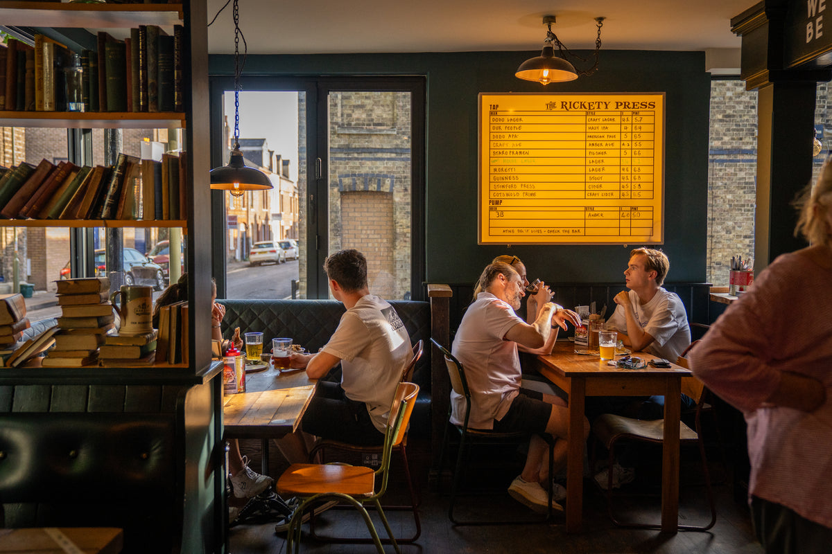 Customers eating at a window table in a cosy pub with bookshelves