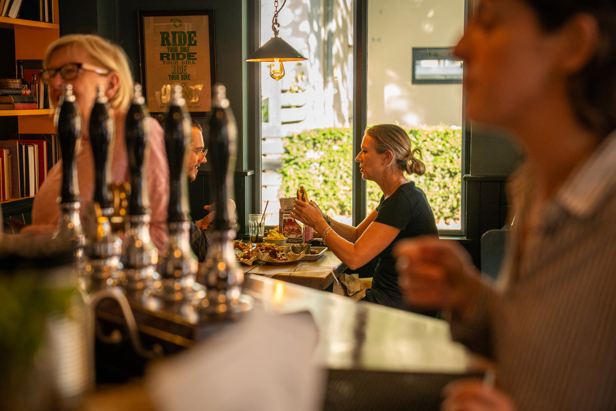 Customers eating at a window table next to the bar's beer taps