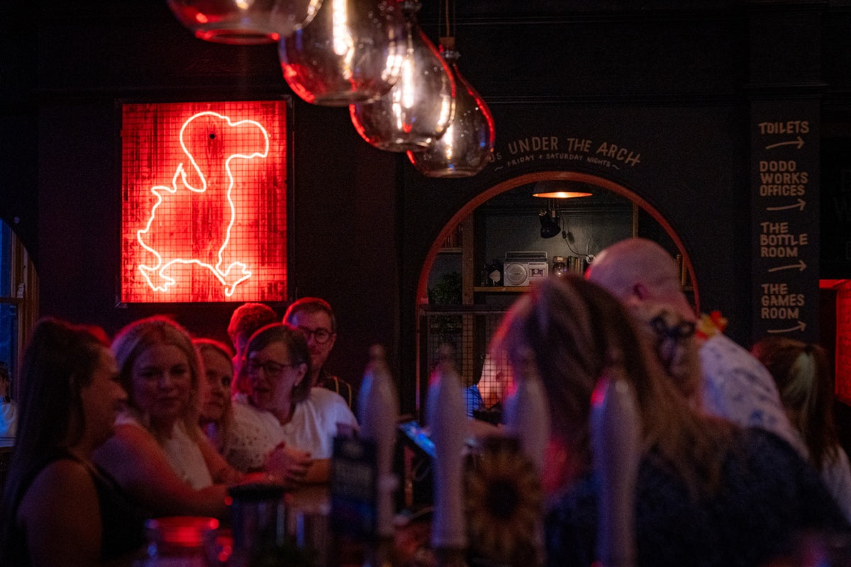 Evening crowd at the bar beneath a red neon dodo sign