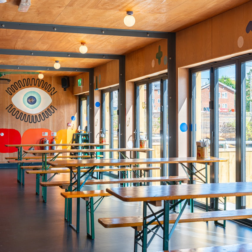 Bright back room at The High Horse with benches and a painted eye mural