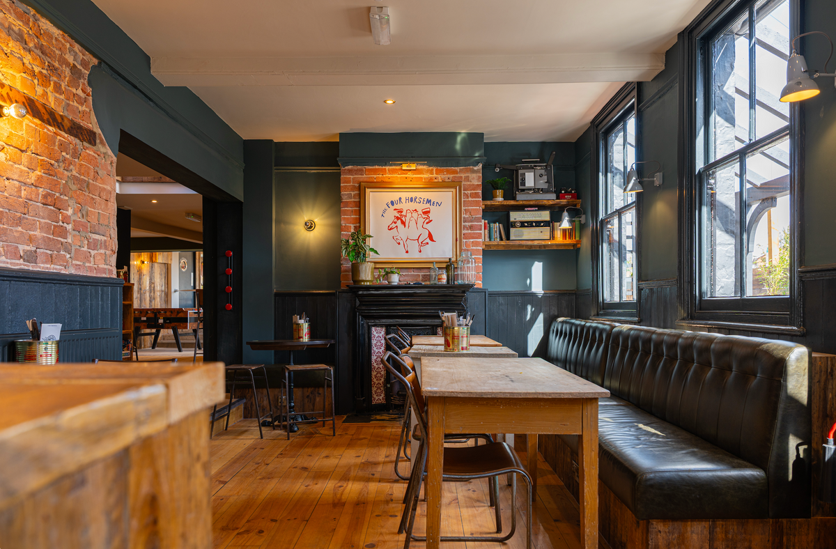 Interior of The High Horse with leather booth seating, a fireplace and wooden tables