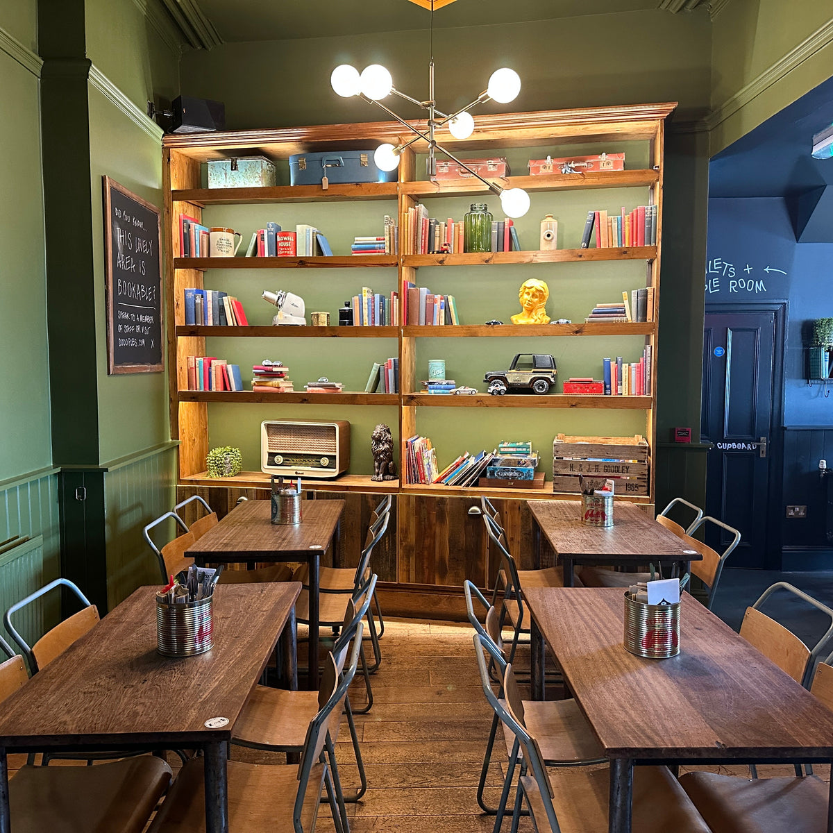 Pub dining area with wooden tables in front of a large bookshelf