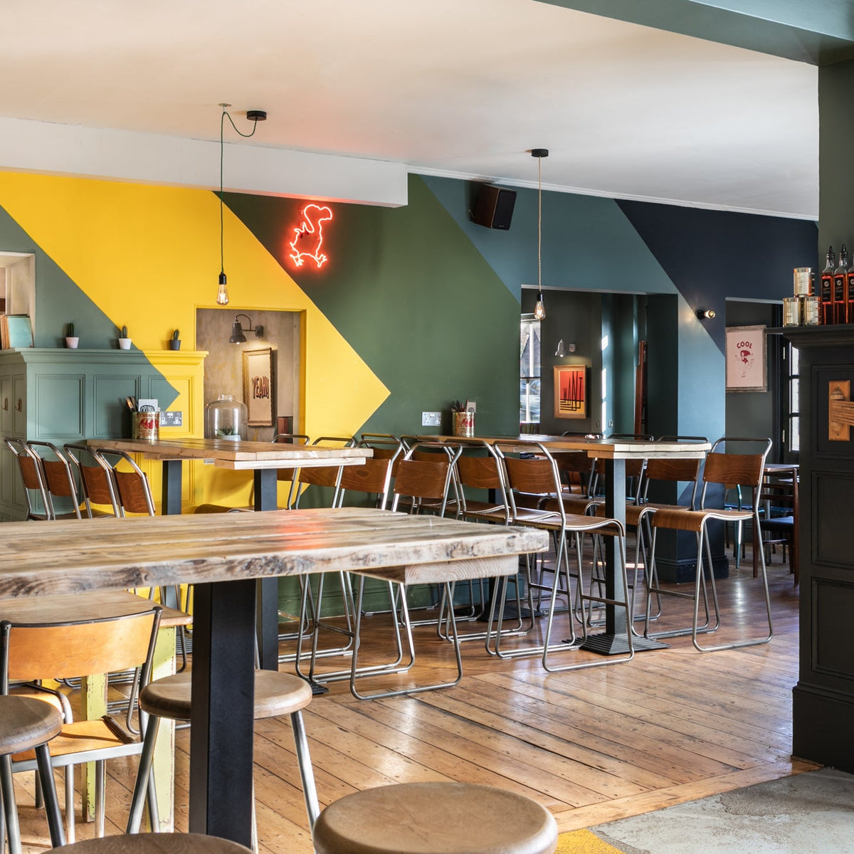 Interior of The Last Crumb with high tables, stools and a red neon dodo sign
