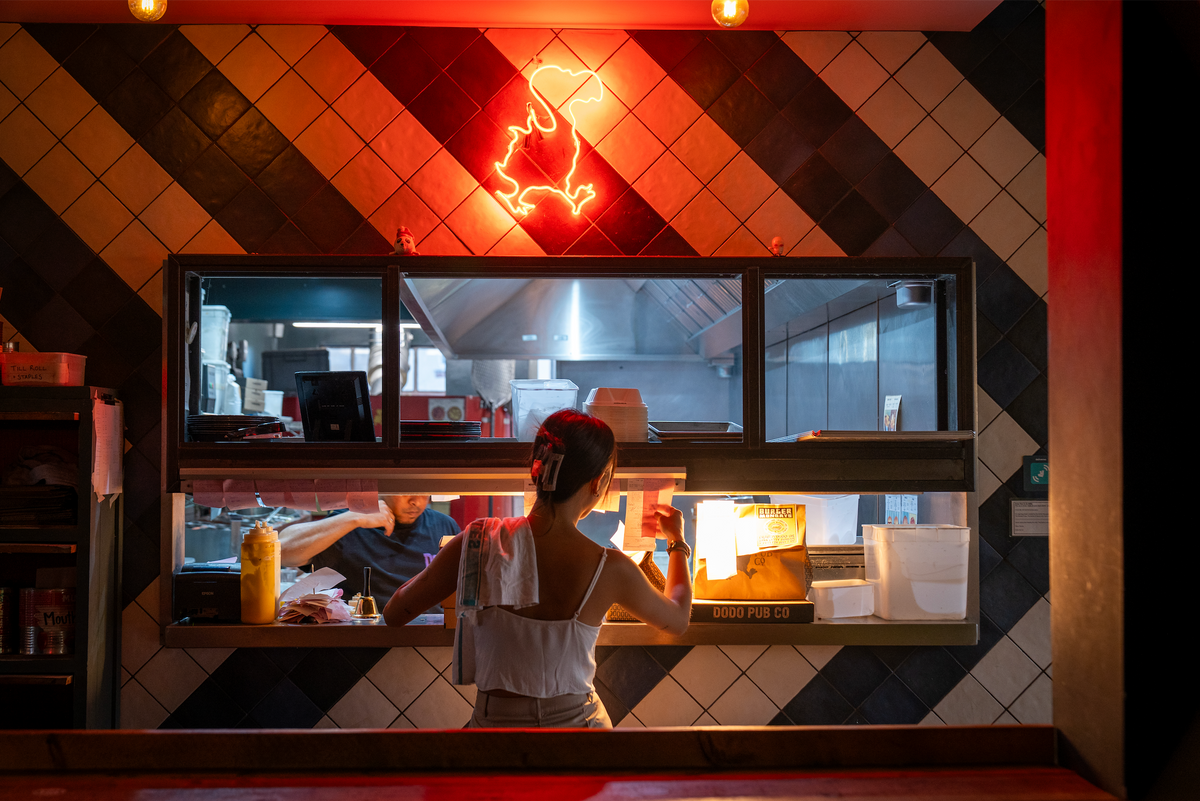 Kitchen serving hatch at The Up In Arms beneath a red neon dodo sign
