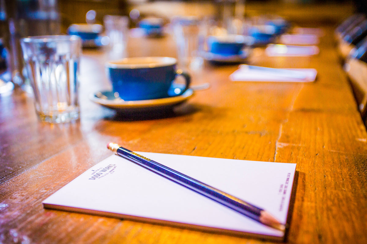 Meeting table set with notepads, pencils and blue coffee cups