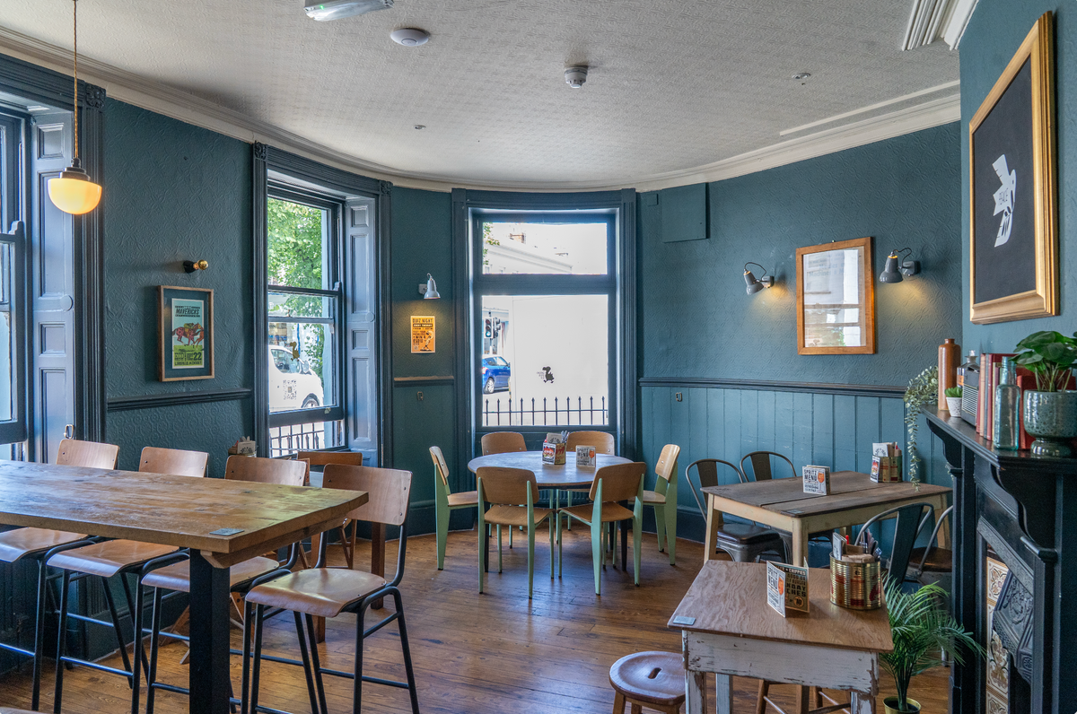 Interior of The Airs & Graces with wooden tables and large windows