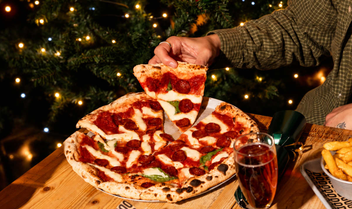 Pepperoni pizza being shared at a table in front of a Christmas tree