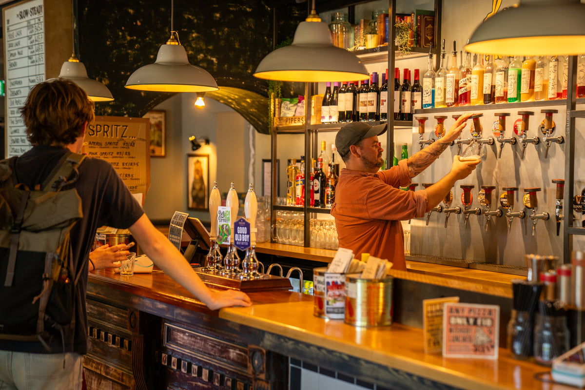 Bartender pouring drinks behind a well-stocked pub bar