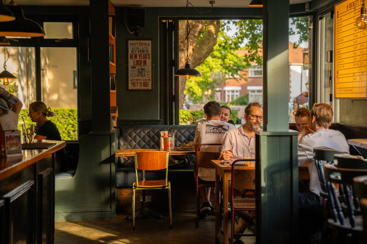 Sunlit pub dining room with customers at tables and booths