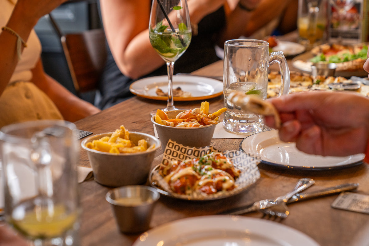 Friends sharing fries, loaded dishes and drinks around a pub table