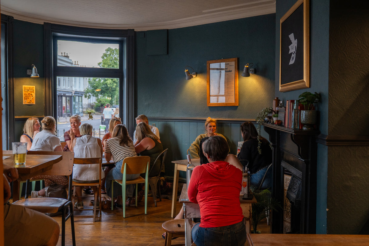 Customers dining in the bright bay-windowed room at The Airs & Graces