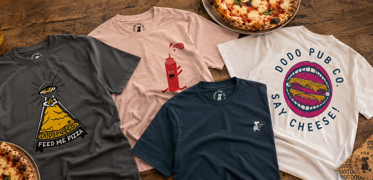 Dodo Pub Co T-shirts laid out on a table next to pizzas