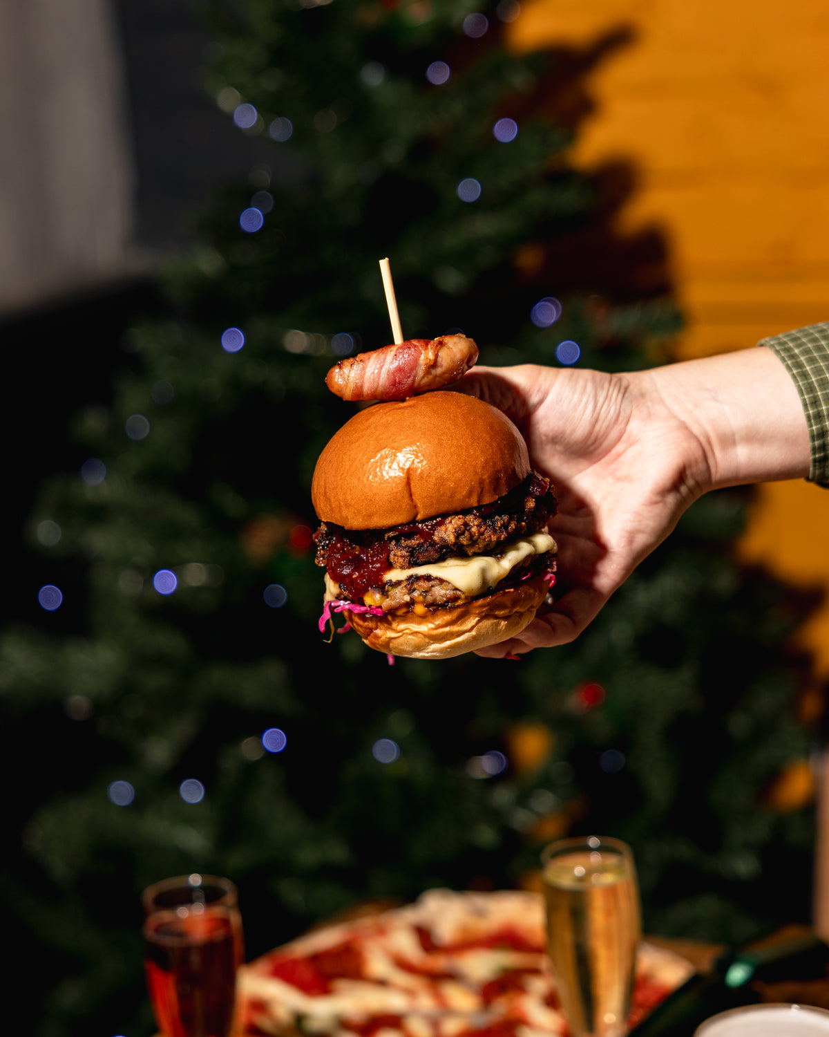 Burger held up in front of a lit Christmas tree