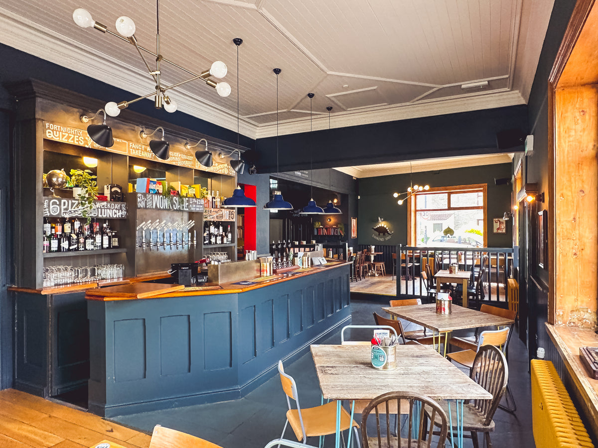 Blue-panelled pub bar with wooden tables and pendant lights