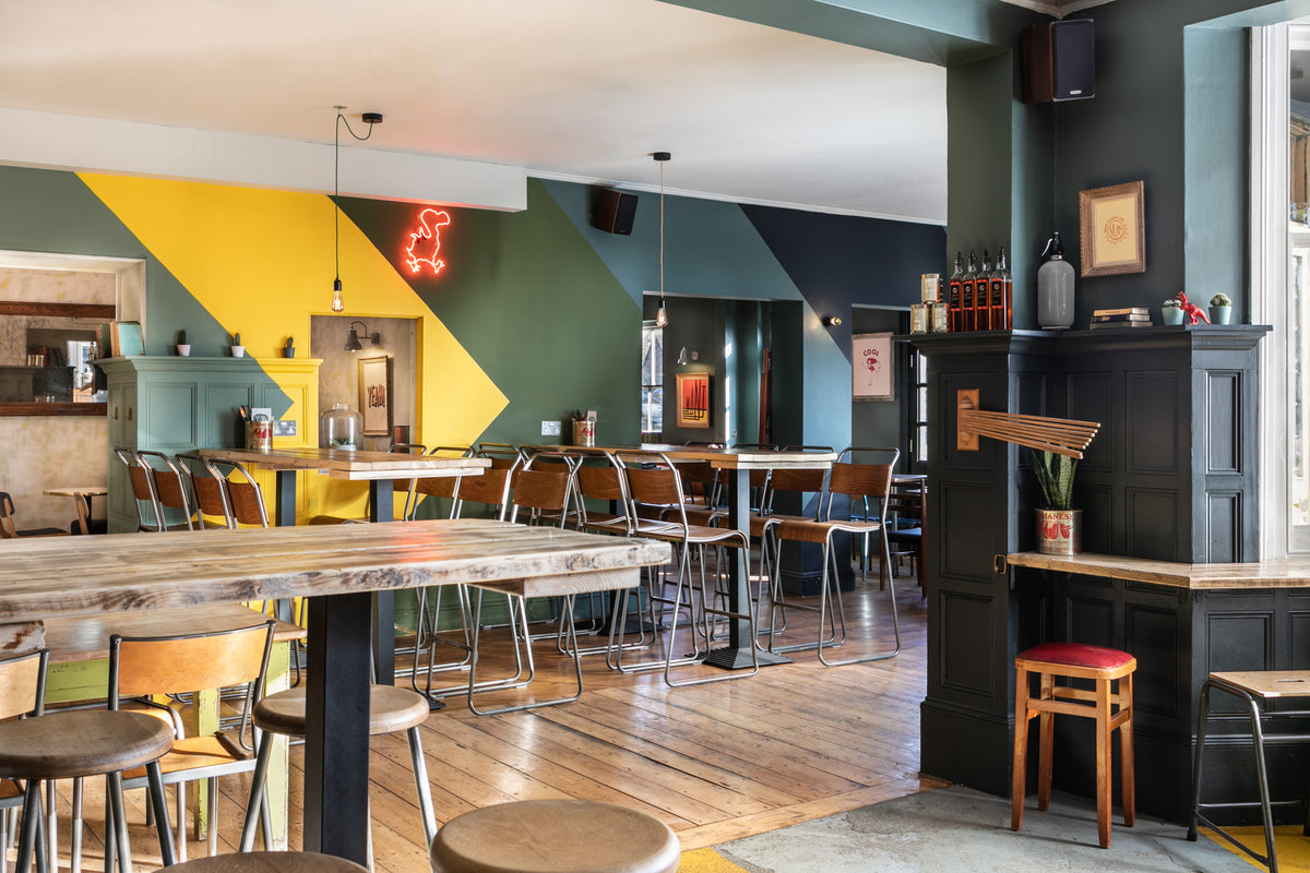 Interior of The Last Crumb with high tables, stools and a colourful painted wall