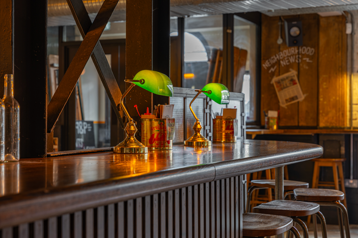 Bar at The Part & Parcel with green banker's lamps and high stools