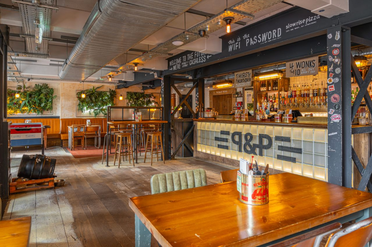 Bar at The Part & Parcel with wooden tables, booth seating and hanging plants