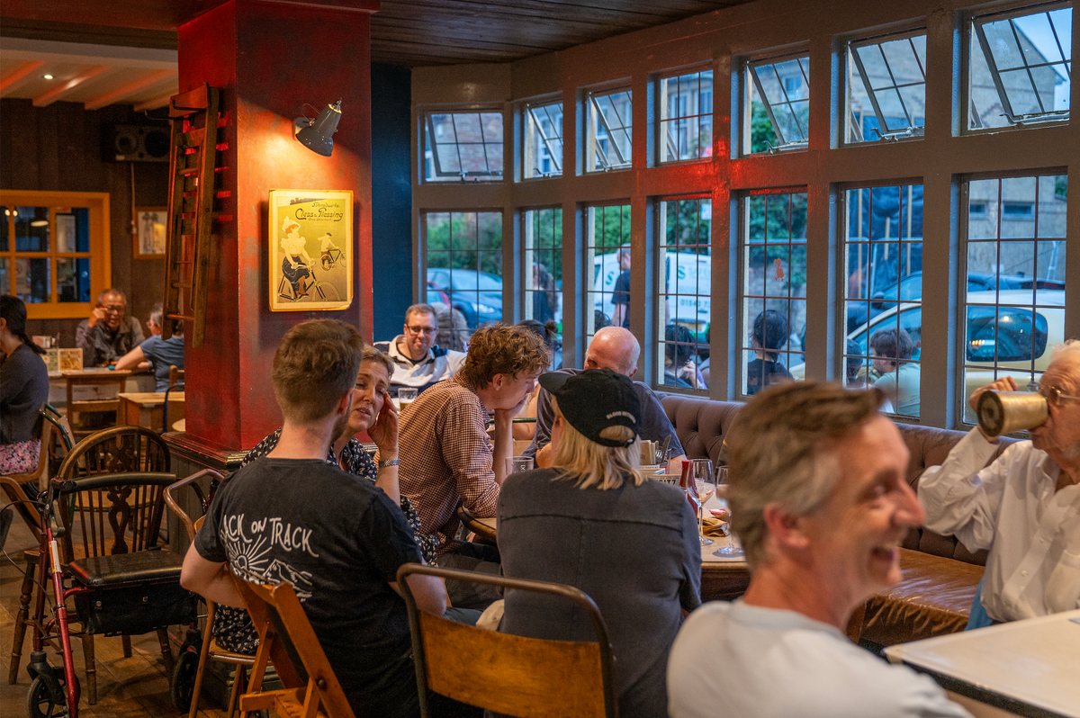 Busy evening inside The Rusty Bicycle with customers at tables by the windows