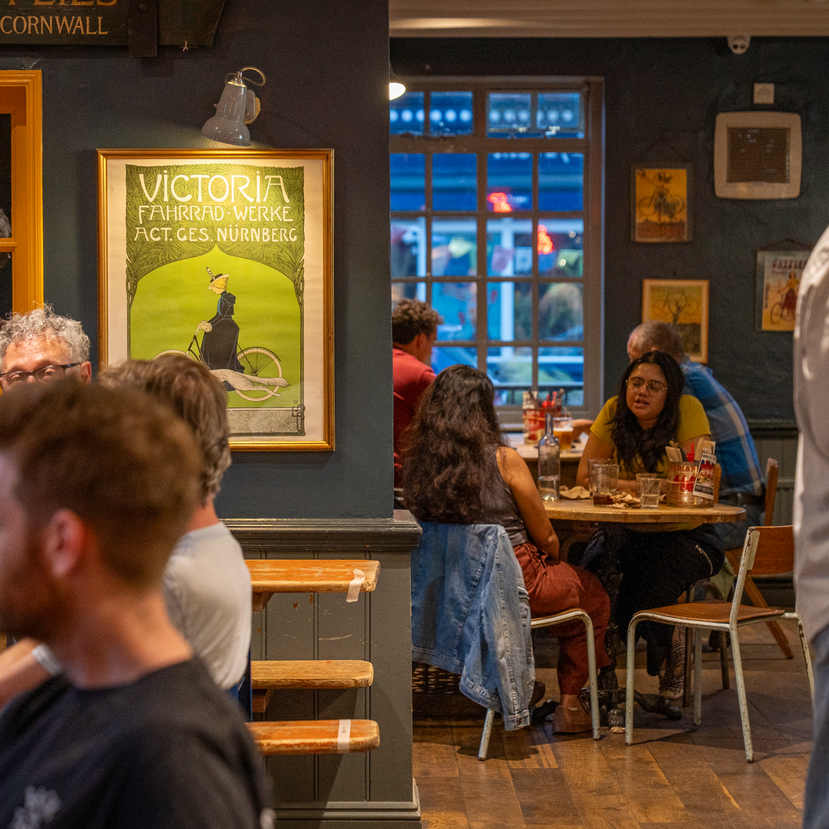 Customers at tables inside The Rusty Bicycle with vintage posters on the walls