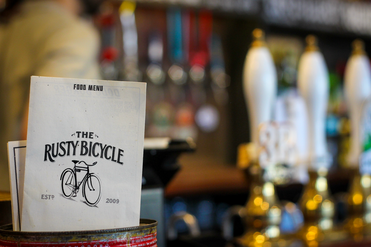 The Rusty Bicycle food menu on the bar in front of beer taps