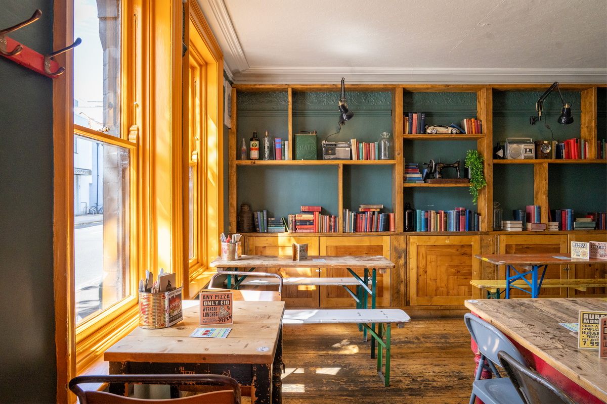 Sunlit interior of The Rickety Press with wooden tables and bookshelves