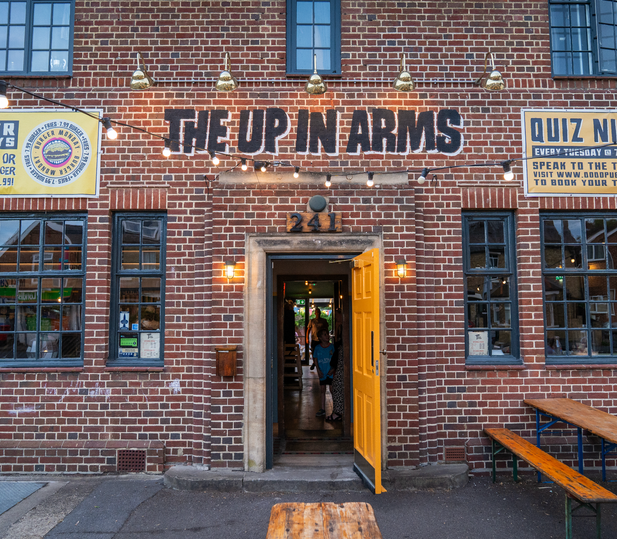 Brick front entrance of The Up In Arms with an open yellow door